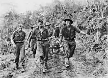 Soldiers carry a stretcher upon which another man lies