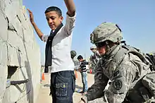 Image 24U.S. Army soldier searches an Iraqi boy, March 2011. (from History of Iraq)