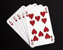 Five playing cards – the ace, king, queen, jack and ten of hearts – spread out in a fan.
