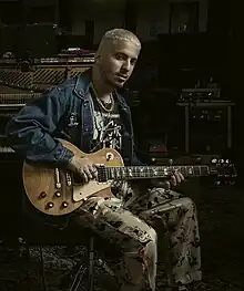 Watt seated with an electric guitar, surrounded by studio equipment