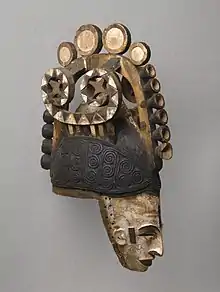 Igbo maiden spirit helmet mask (Agbogho Mmwo); early 20th century; 50.2 x 14.6 x 30.5&nbsp;cm (193⁄4 x 53⁄4 x 12 in.); Brooklyn Museum. This helmet mask has long narrow face, painted white; narrow protruding sharp nose; slit eyes; open mouth showing teeth; small ears