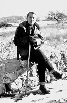 René Char sitting on a wall with a walking stick
