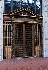 An entrance showing ornate bronze work on and around the gates covering the doors
