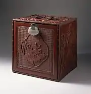 Japanese chest with cartouche showing figures on donkeys in a landscape; 1750–1800; carved red lacquer on wood core with metal fittings and jade lock; 30.64 x 30.16 x 12.7&nbsp;cm; Los Angeles County Museum of Art (USA)