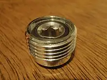 A screw plug to fit inside a DIN socket of a pillar valve. The central orifice is in the form of an Allen socket on the face which accepts the Yoke fitting. Both ends have face sealing O-ring grooves.