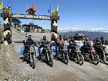 Six motorcyclists at a war memorial in the mountains