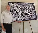 Frankétienne poses in front of his acrylic on canvas.