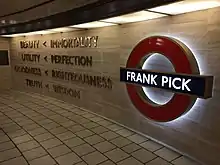 Words mounted on a cream-coloured stone wall next to a large, illuminated London Underground symbol (red ring with a blue bar) with the words "Frank Pick" on the blue bar