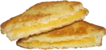 A toasted square sandwich cut into two triangle halves, showing a cross-section. There is a layer of melted cheese in the sandwich.