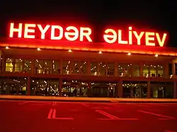 Two-storey building with a concrete-and-glass façade with a large neon sign reading "Heydər Əliyev" on the roof