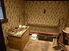 Small bedroom has bedframe with spring and small dresser.