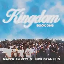 The album cover for Kingdom Book One is an overhead photo of Maverick City Music, Kirk Franklin, and the inmates of Everglades Correctional Institution and a relatively clear blue sky. The text on the image reads "Kingdom Book One" above the crowd, inscribed in a white font resembling clouds, while the artist credit "Maverick City x Kirk Franklin" is inscribed near the bottom of the image.