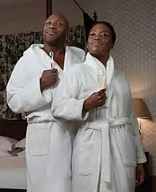 A black woman and a black man wearing white bathrobes