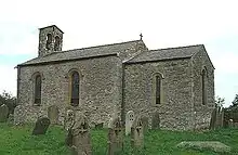 A small, simple stone church. On the left is the nave with a bellcote at the far end, and on the right a smaller chancel