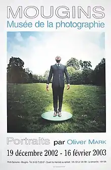 Curator Okwui Enwezor in a suit on a green meadow.