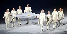 Eight people carrying a large flag within a spotlight