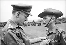 Black and white photograph of Brigadier (Oliver) David Jackson pinning the Military Cross on Harry Smith in military uniform, 1967