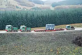 Two MAN SE ballast tractors pulling and one Mercedes pushing a 100,000&nbsp;kg (220,000&nbsp;lb) transformer on 10-axle lowboy