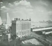 A multi story building seen from above with a river visible behind it