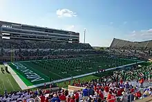 A marching band performs on the field of a football stadium.