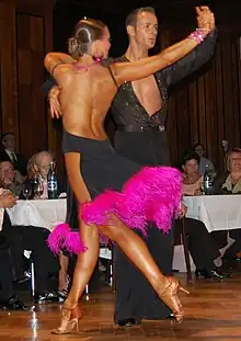 Image 17Latin dancers in their costumes. The woman is wearing backless dress with deep slits on its lower portion, while the man is wearing a shirt with top buttons open. (from Fashion)