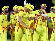 Men in cricket outfits smiling and high-fiving
