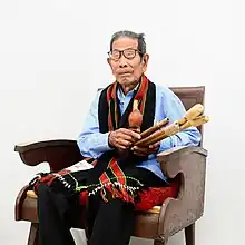 Thanga Darlong official portrait holding the traditional musical instrument 'Rosem'