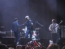 Several men performing onstage playing and singing into a microphone