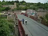 Pedestrians walking over a bridge with red-brown hand rails