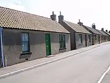 Terraced row of single storey cottages finished in stone and render
