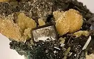A rare and fine combination plate from the Tsumeb Mine. Glassy, mostly transparent, smoky-colored wulfenite crystals with sharp beveled edges are richly and aesthetically scattered on the matrix. Bundles of lustrous, yellowish-tan mimetite are concentrated at the top of the piece, and the largest wulfenite, at 9&nbsp;mm, is aesthetically framed by two mimetite crystal clusters.
